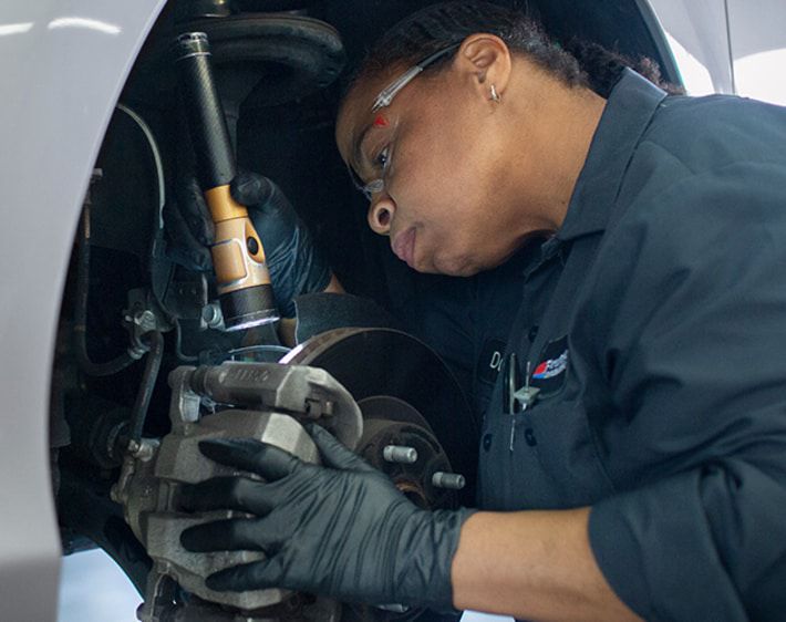 Firestone technician inspecting brake calipers