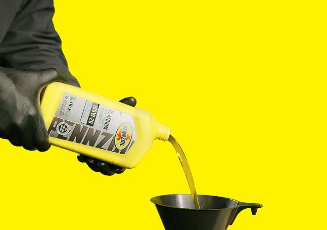 A technician pouring Pennzoil full synthetic oil into a funnel.
