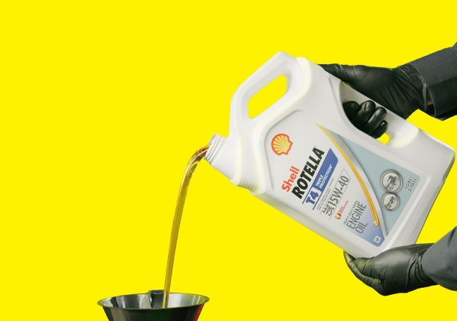 A technician pouring Shell Rotella diesel engine oil.