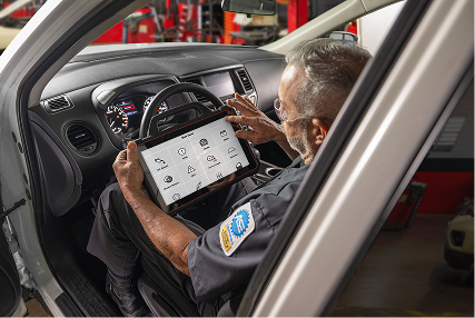 An auto technician reviewing vehicle inspection details on a tablet.