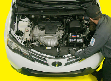 A technician reviewing vehicle components under the hood of a car.