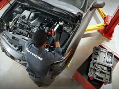Bird's eye view of a technician working under the hood of a car.