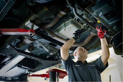 Technician working on the chassis of a raised car.