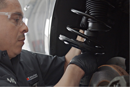 Technician working on the suspension of a raised car.