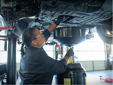 Technician working on the underside of a raised vehicle.