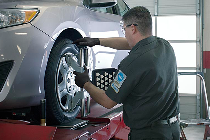Technician working on the wheel of a raised vehicle.