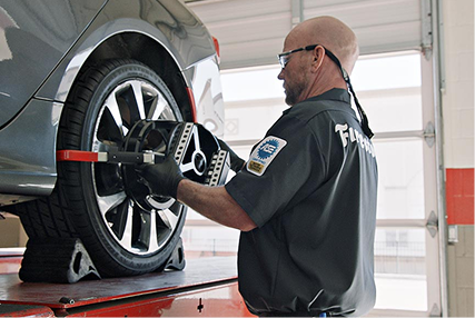 Technician working on the wheel of a raised vehicle.