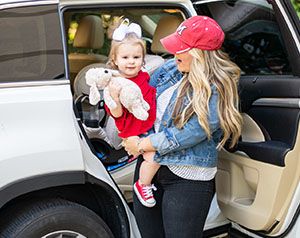 Mom holds baby in front of car