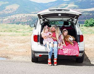 Family sitting on SUV tailgate while having fun on side of the road