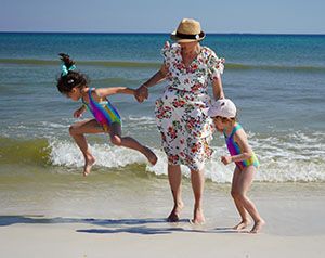 Woman in flowered dress with two girls in colorful swimsuits