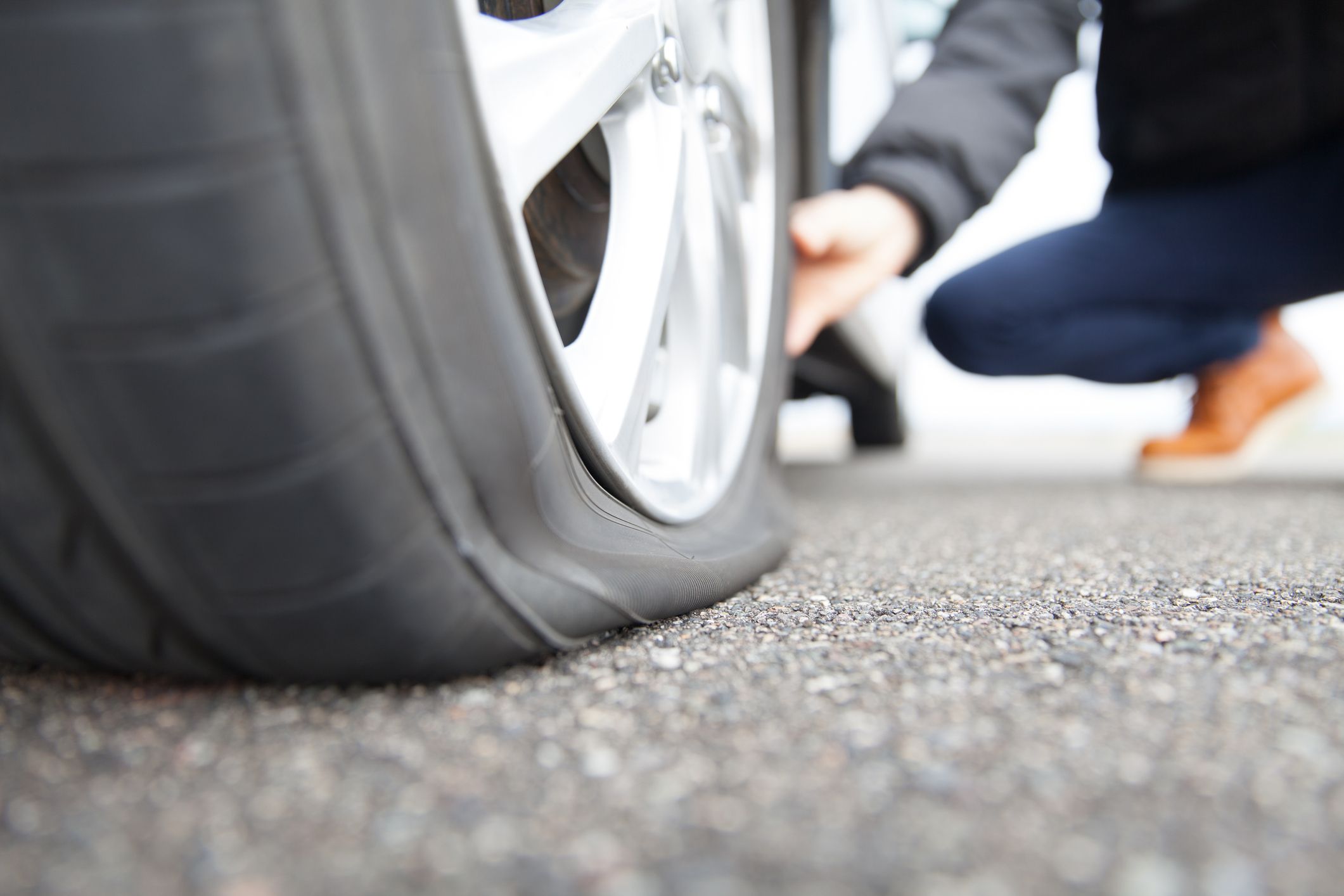 Man touching a flat tire on the roadside.