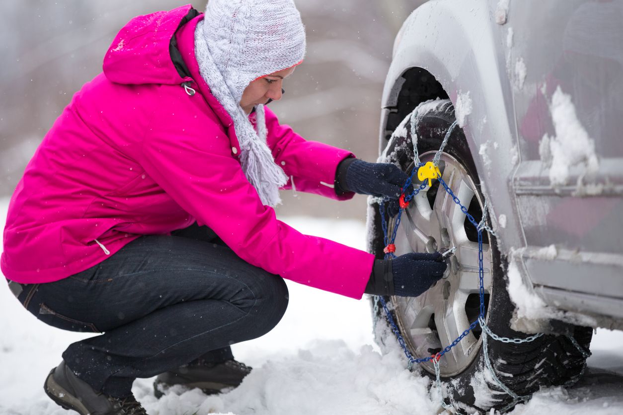 Woman putting  snow chain on wheels