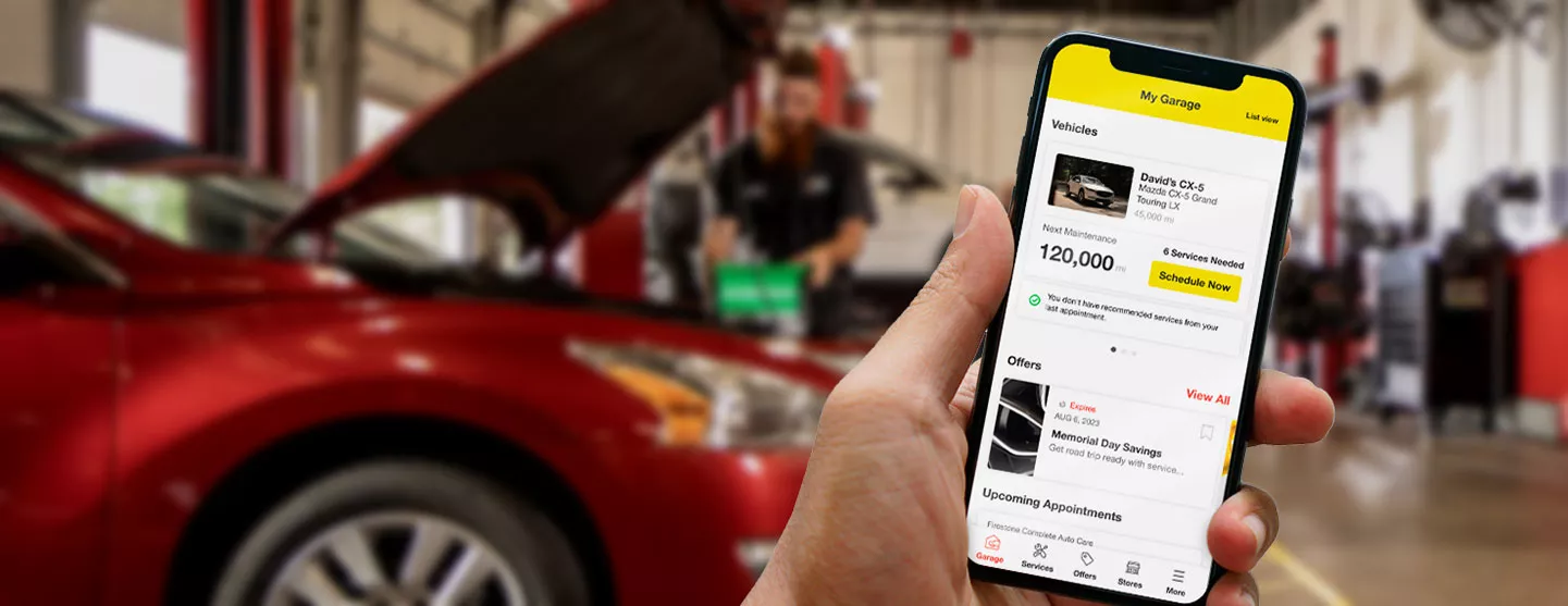 Hand holding mobile device showing Tires Plus mobile app