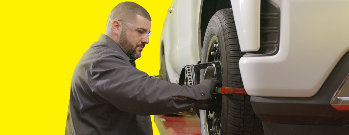 Closeup of tire clamped with aligner undergoing auto wheel align