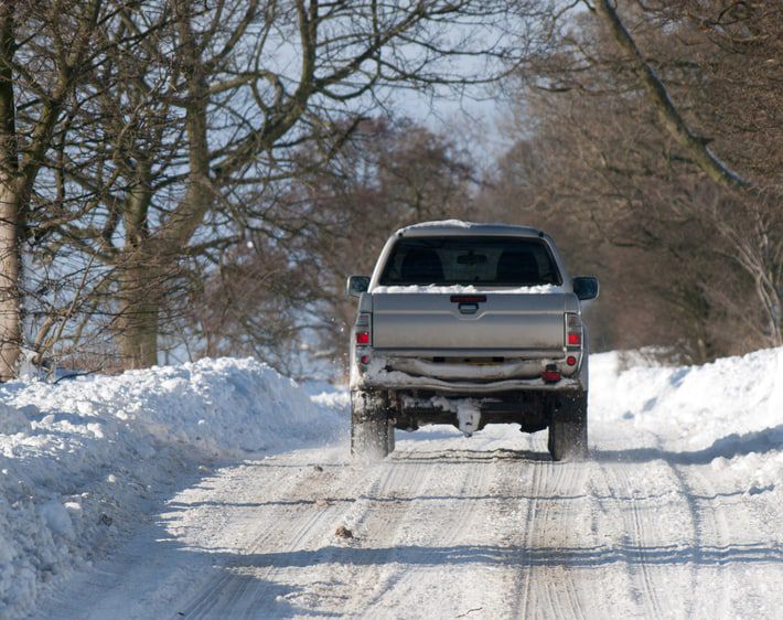 Truck driving down a snowy road