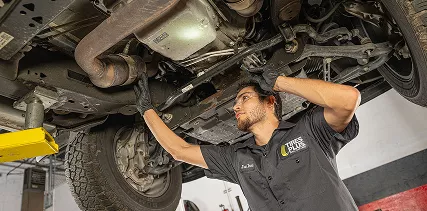An expert technician works under the chassis of a car.