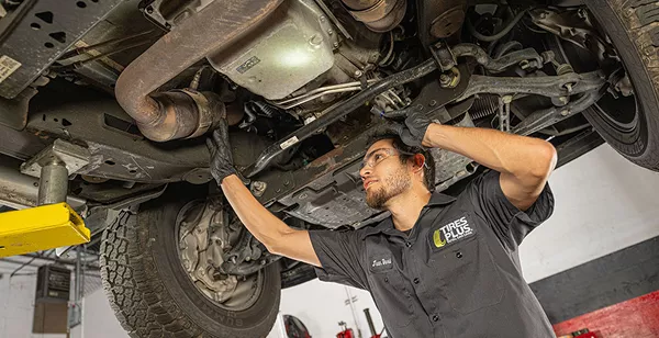 A technician reviewing vehicle components under the hood of a car.