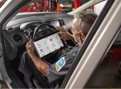 An auto technician reviewing vehicle inspection details on a tablet.
