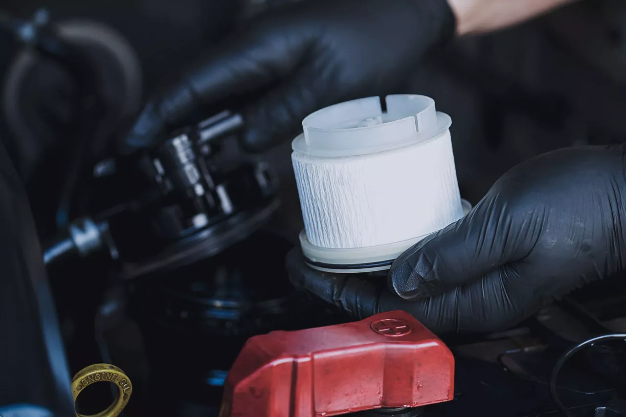 Closeup of technician's hands holding a fuel filter.