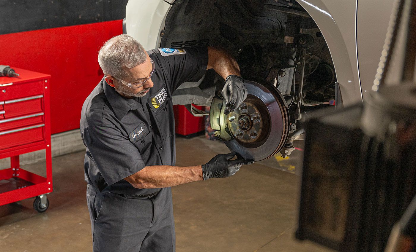 male vehicle mechanic inspecting vehicle brakes