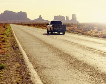 Pickup truck driving down desert road 