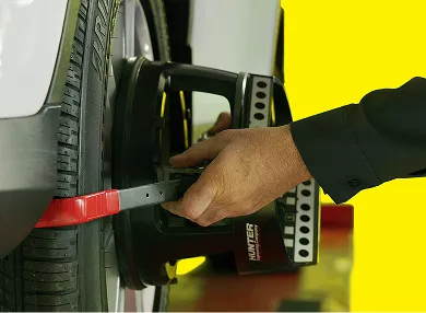 A technician checking wheel and tire alignment.
