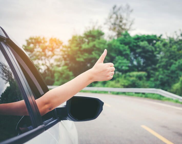 woman giving thumbs up out the window of a Toyota Camry