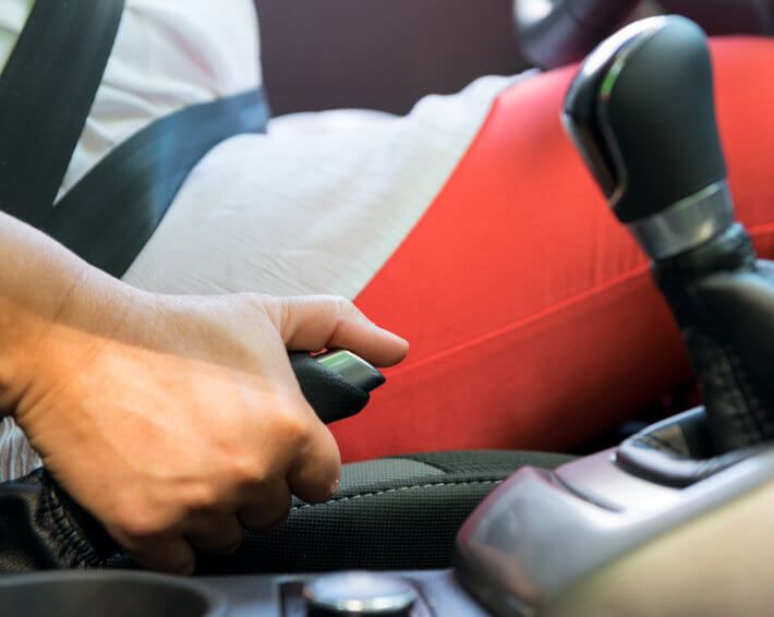 Woman in red pants pulling parking brake in car after brake failure