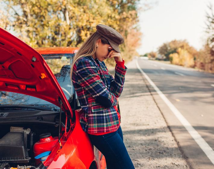 Woman leaning on a broken down car