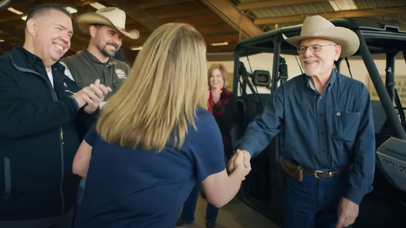 A Can-Am dealer employee giving a side-by-side Defender to a man of a non-profit organization