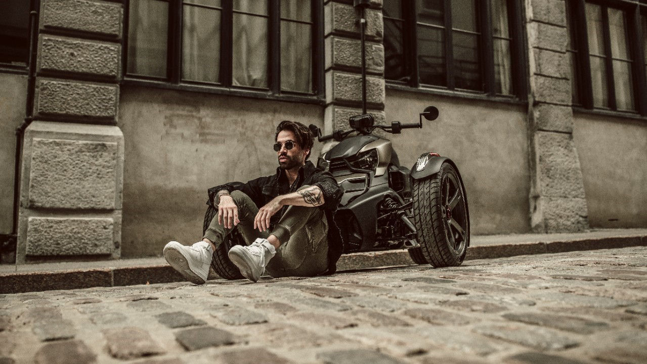 Man zit op straat in de buurt van een Can-Am Ryker