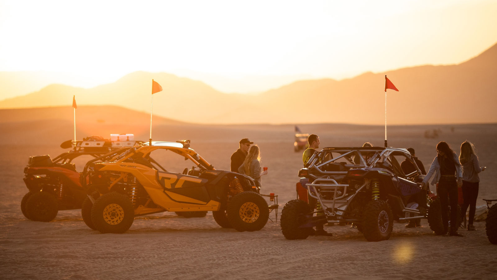 Un grupo de personas con dos vehículos Can-Am al atardecer 