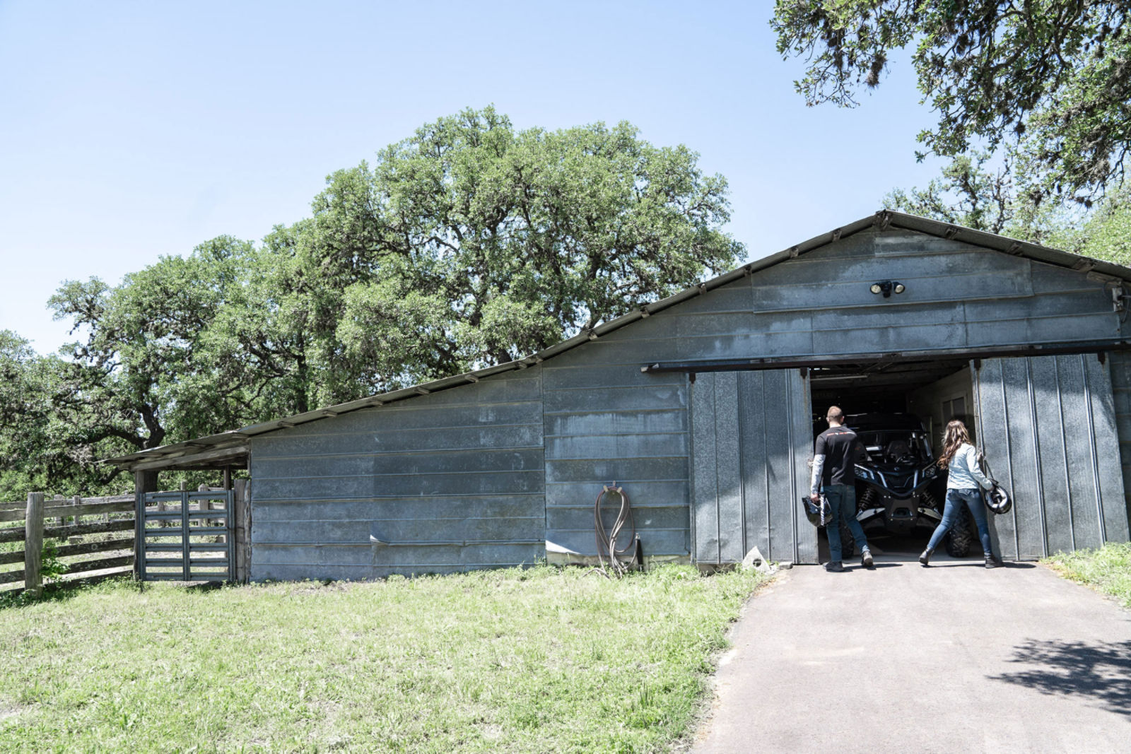 A couple opening a garage with a Can-Am Maverick Sport inside
