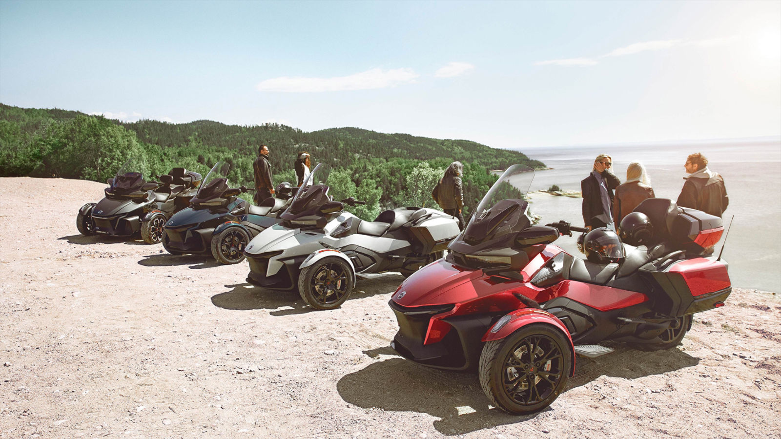 Several Can-Am Spyder three-wheelers and their riders parked at the edge of a cliff