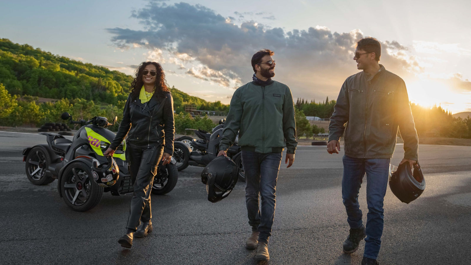 Trois personnes en vêtements de conduite se dirigeant vers la caméra au coucher du soleil