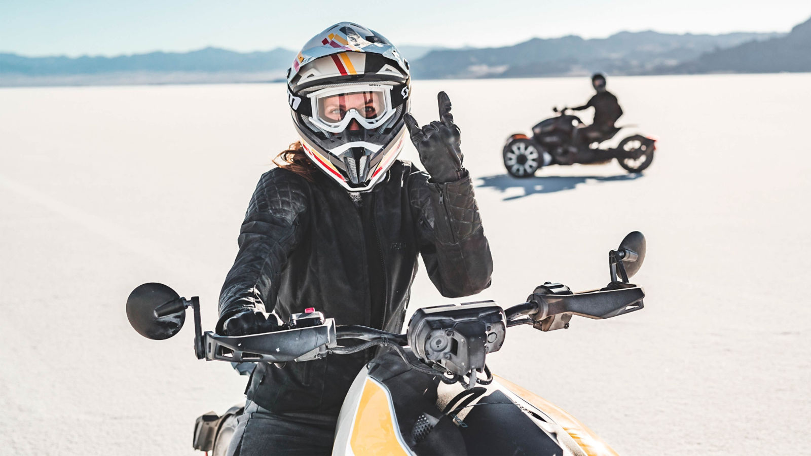 Ein Fahrer auf einem Can-Am Ryker zeigt ein Handzeichen, während ein zweiter Fahrer im Hintergrund nach links fährt