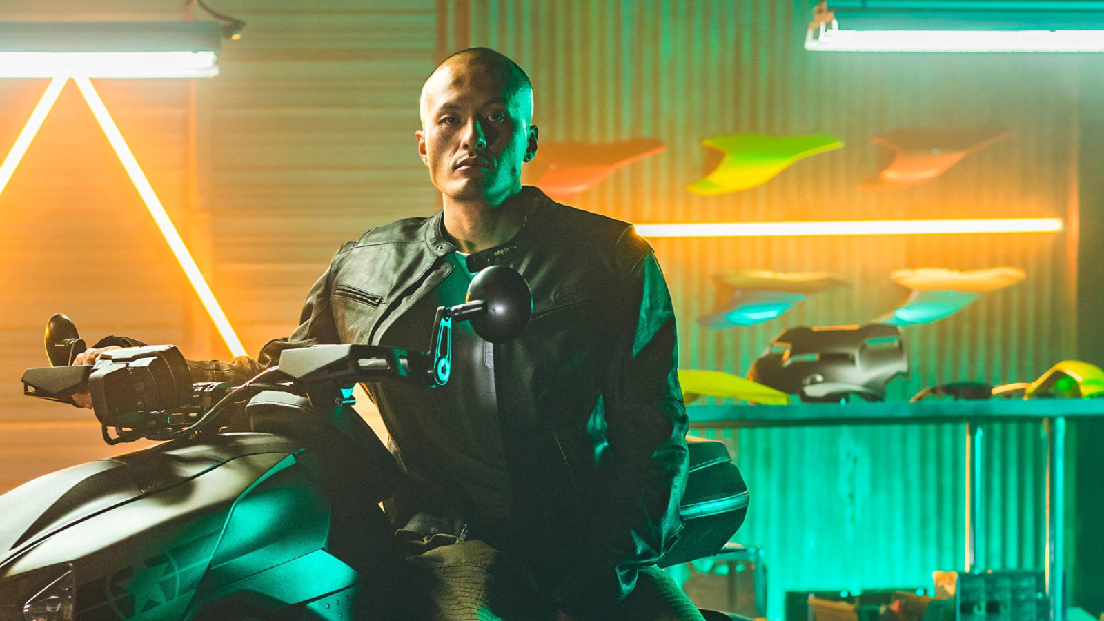 A man sitting on his Can-Am vehicle in front of a display of panels, accessories and riding gear