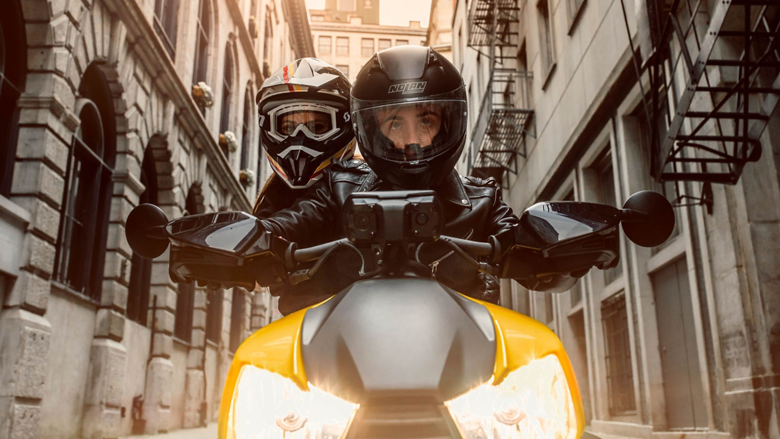 Couple riding on Can-Am Ryker vehicle with yellow shock panels