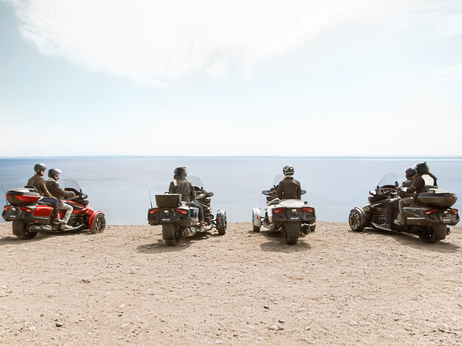 A group of friends admiring the open water while sitting on their Can-Am vehicles