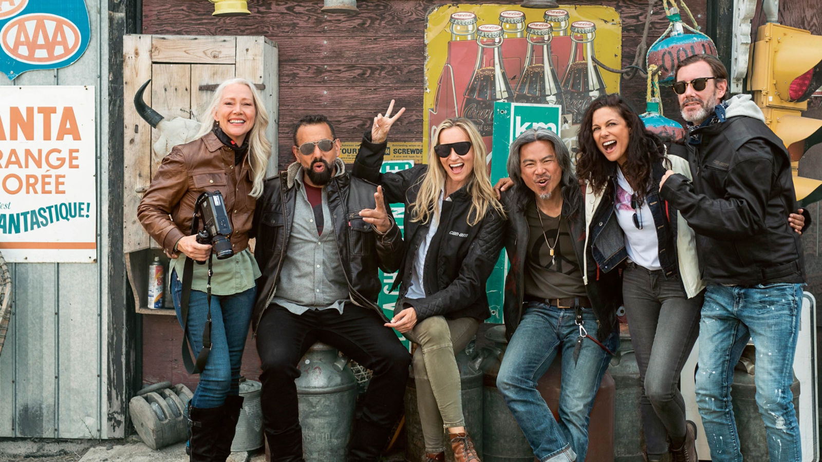 A group of friends smiling and posing in front of a rustically decorated mural