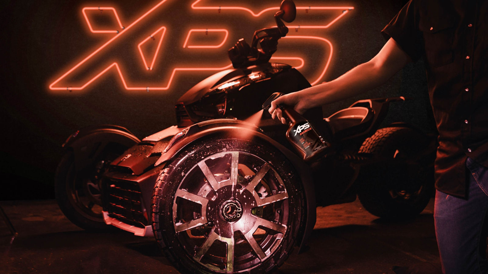A Can-Am vehicle with a neon XPS sign lit in the background