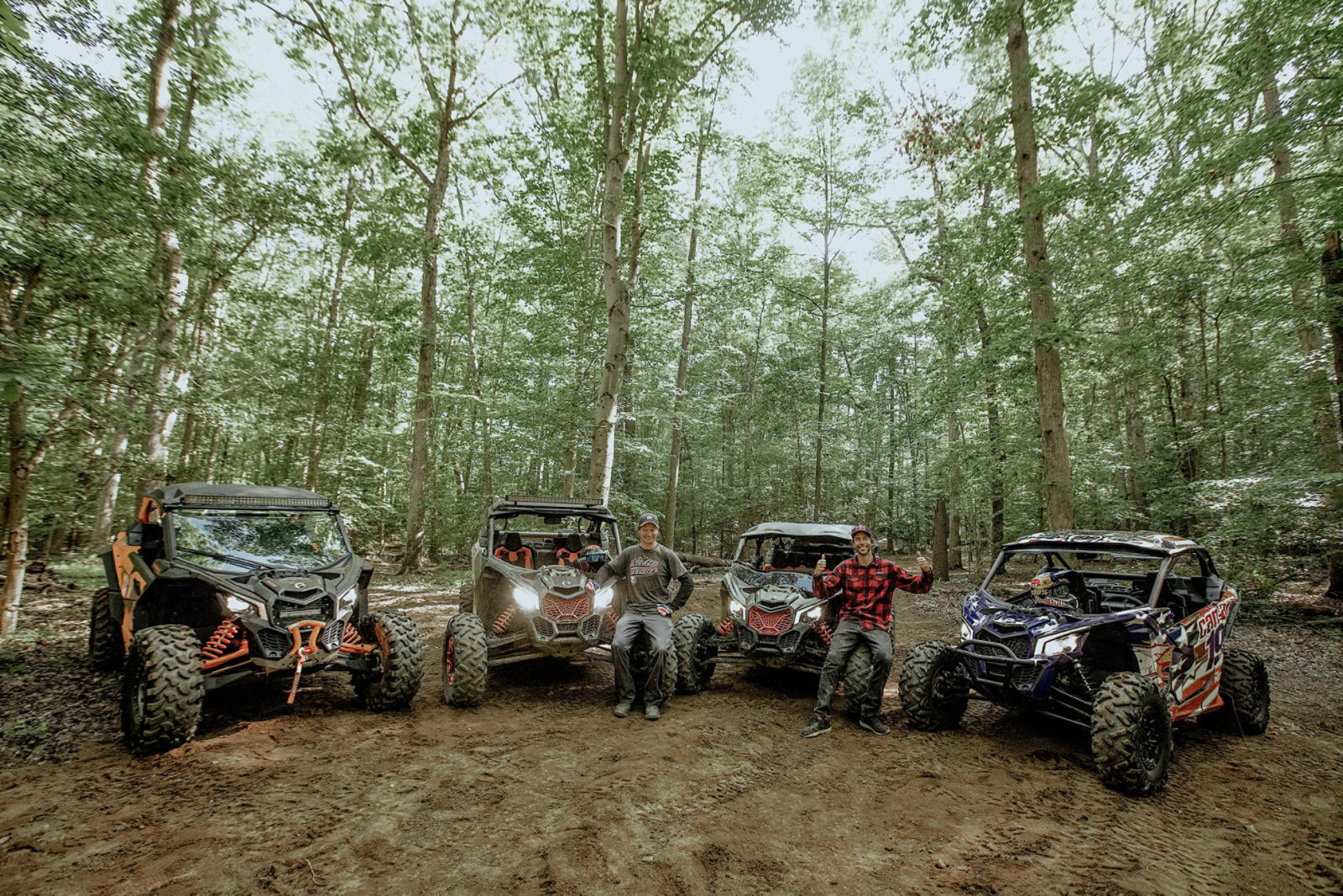 Two men and four Can-Am side-by-sides in a forest