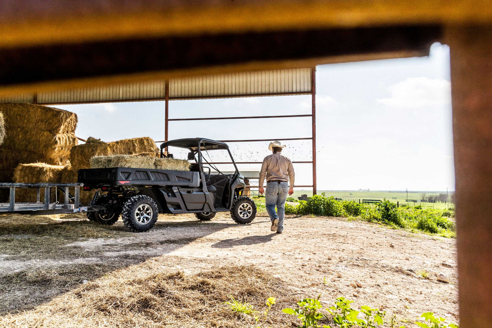 Man walking towards a Can-Am Defender PRO filled with hay on the farm