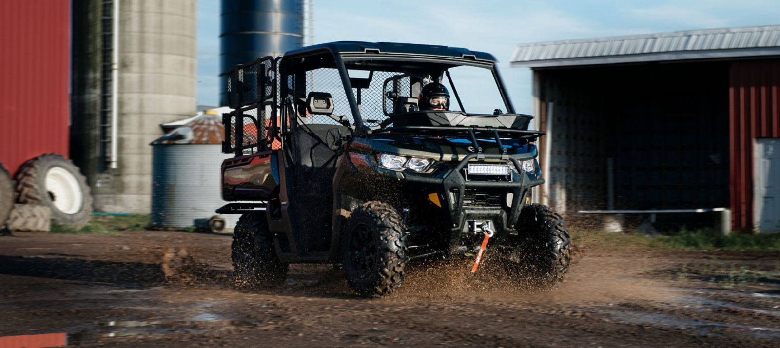 Man riding a Can-Am Defender side-by-side at the farm