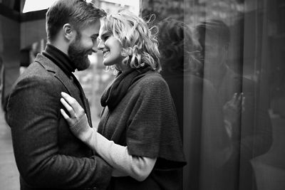 Black and white image of a newly engaged couple bundled up in coats leaning in to kiss