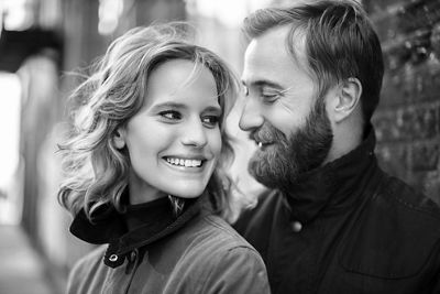 Black and white close up image of newly engaged couple looking at each other and smiling