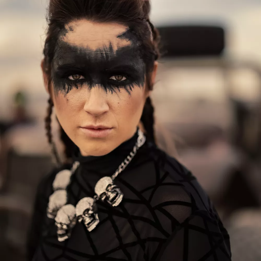 Person with a Skull Necklace and Black Paint on Their Eyes