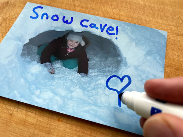 Photo d’une fille dans un fort de neige avec "Grotte de neige!" écrit dessus