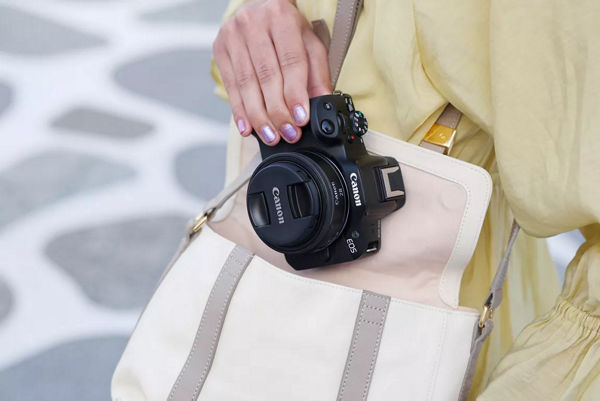 Personne rangeant un appareil photo avec un objectif dans un petit sac