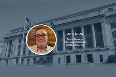 Headshot of John Spiak in front of govt building